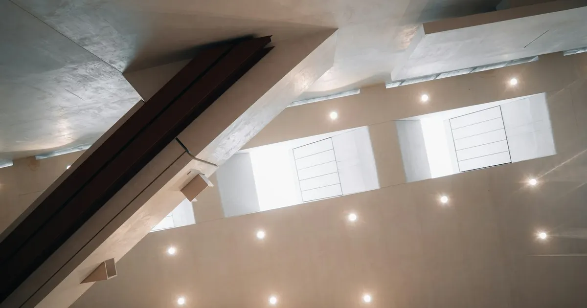 A modern room ceiling fitted with an even grid of warm recessed downlights